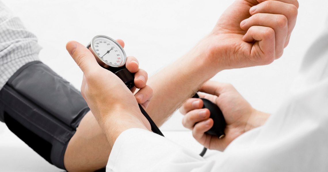 Doctor measuring blood pressure - studio shot on white background